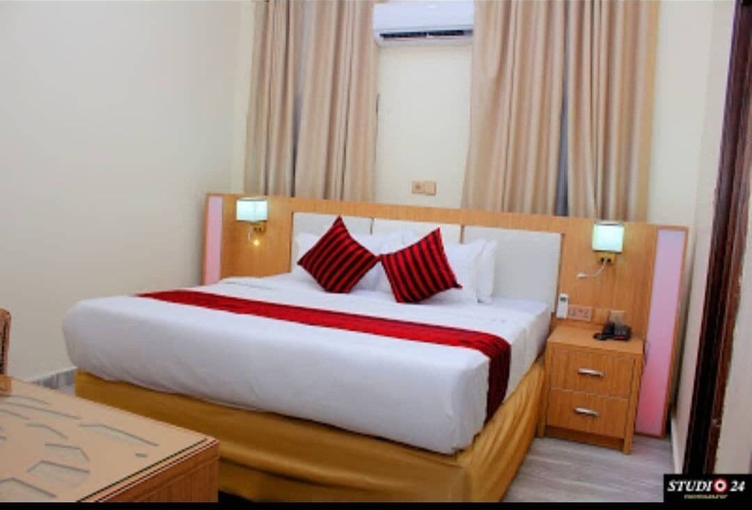 A hotel room with a bed, bedside tables, and curtains.