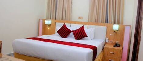 A hotel room with a bed, bedside tables, and curtains.