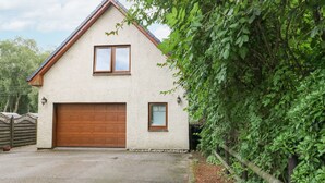 A two-story house with a large garage, a small window, and a door. - Glenmhor Apartment (Fort William)