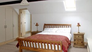 A bedroom with a wooden bed, a wardrobe, a small bedside table, and a nightstand.