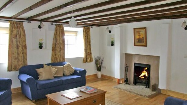 A living room with a blue sofa, a wooden coffee table, a fireplace, and a patterned rug.