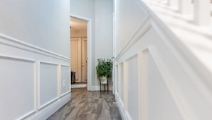 A hallway with white wainscoting and a wooden floor. - 3BR Townhouse Right in Front of Epic Universe! (Orlando)