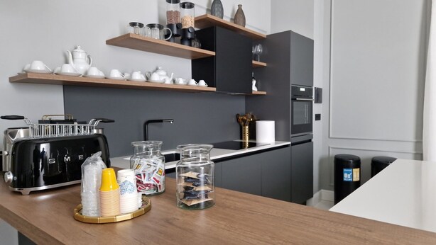 A modern kitchen with a wooden countertop, a toaster, glass jars, and a coffee machine.