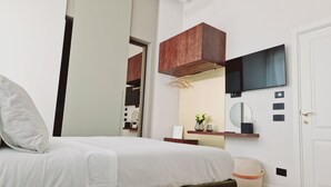A modern bedroom with a bed, a wooden cabinet, a mirror, and a television.