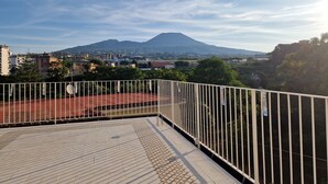 A rooftop terrace with a view of a mountain and surrounding buildings.