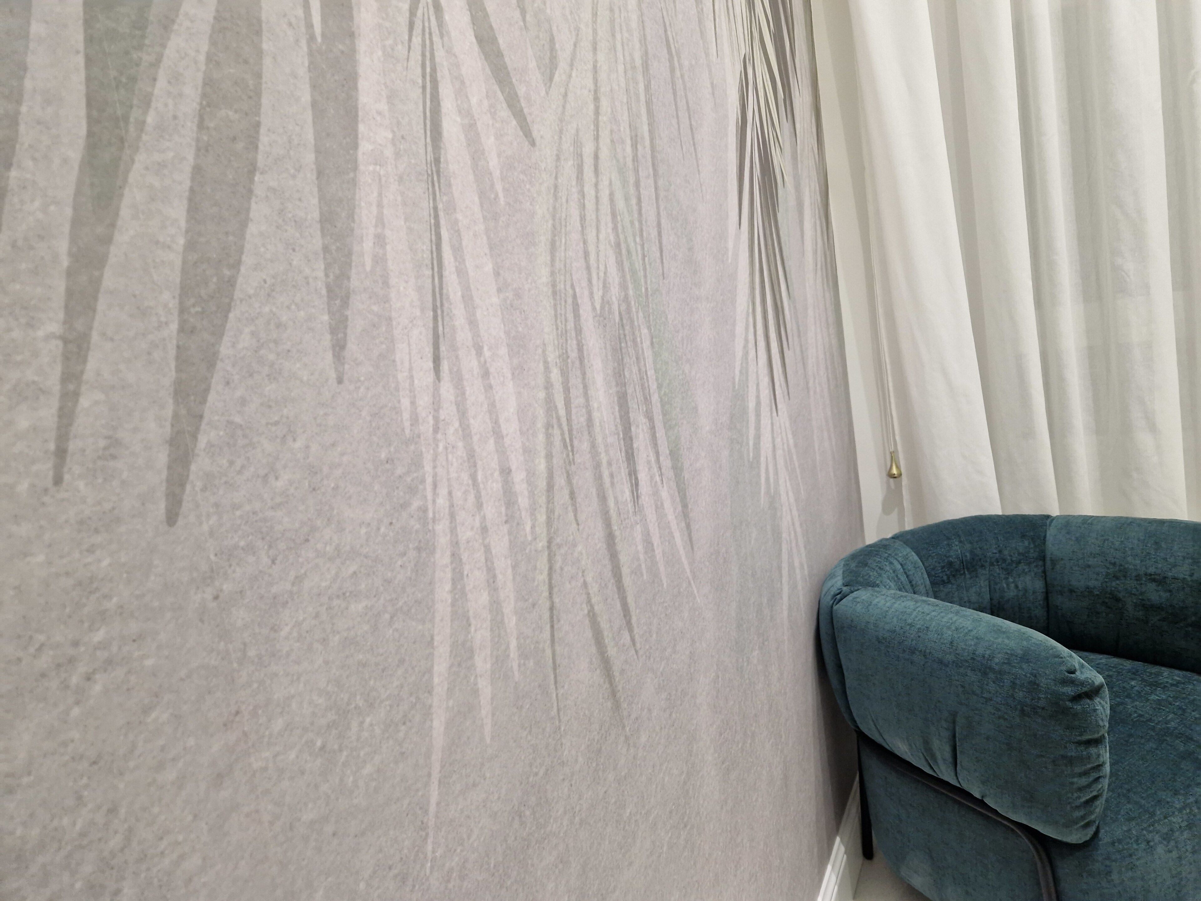 A room with a grey textured wall, a white curtain, and a teal armchair.