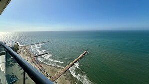 Blick auf die Küste vom Balkon mit Strand, Meer und einer Mole.