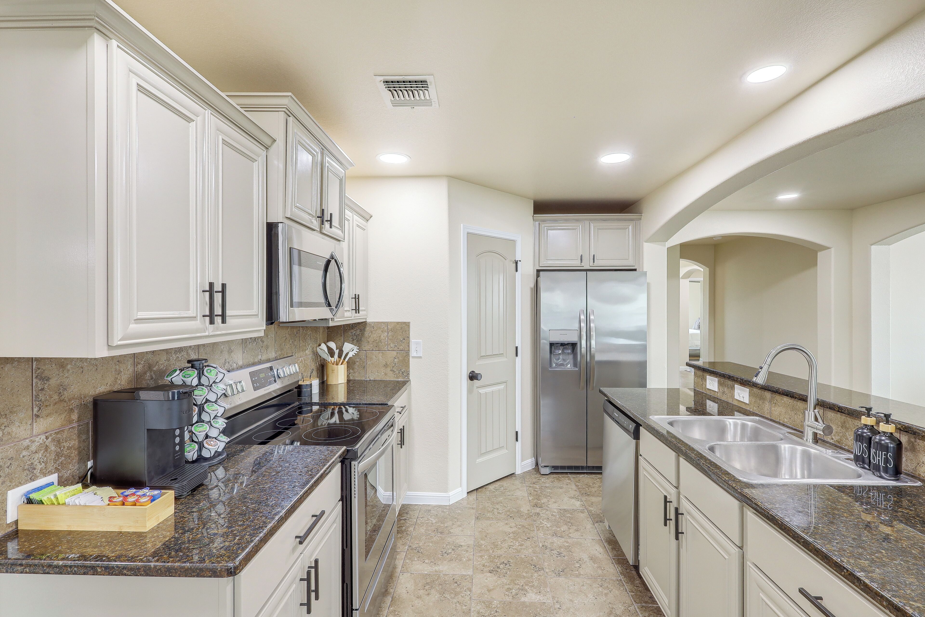 A modern kitchen with white cabinets, stainless steel appliances, a granite countertop, and a built-in oven.