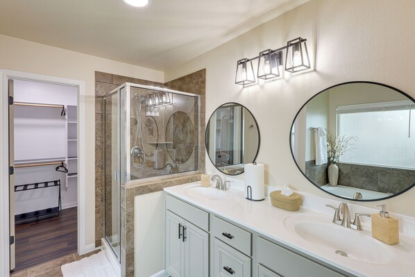 A modern bathroom with a glass shower, a vanity with a sink, and a large mirror. - Private Patio: Modern Killeen Vacation Rental! (Killeen)