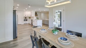 A modern kitchen with white cabinets, a wooden dining table set with bowls, and a hanging light fixture. - Waterfront Hot Springs Home w/ Dock & Porch! (Hot Springs)