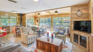 A spacious living room with a large TV, comfortable seating, and a view of a lake. - Kilgore Lakefront Home w/ Private Dock & Pier! (Kilgore)