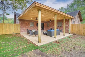 Un porche cubierto con mobiliario exterior, una casa de ladrillo y una valla de madera.