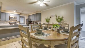 Una cocina moderna con armarios grises, microondas y un comedor con mesa de madera para cuatro.