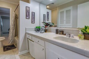 Un baño moderno con tocador blanco, un lavamanos grande y una zona de ducha.