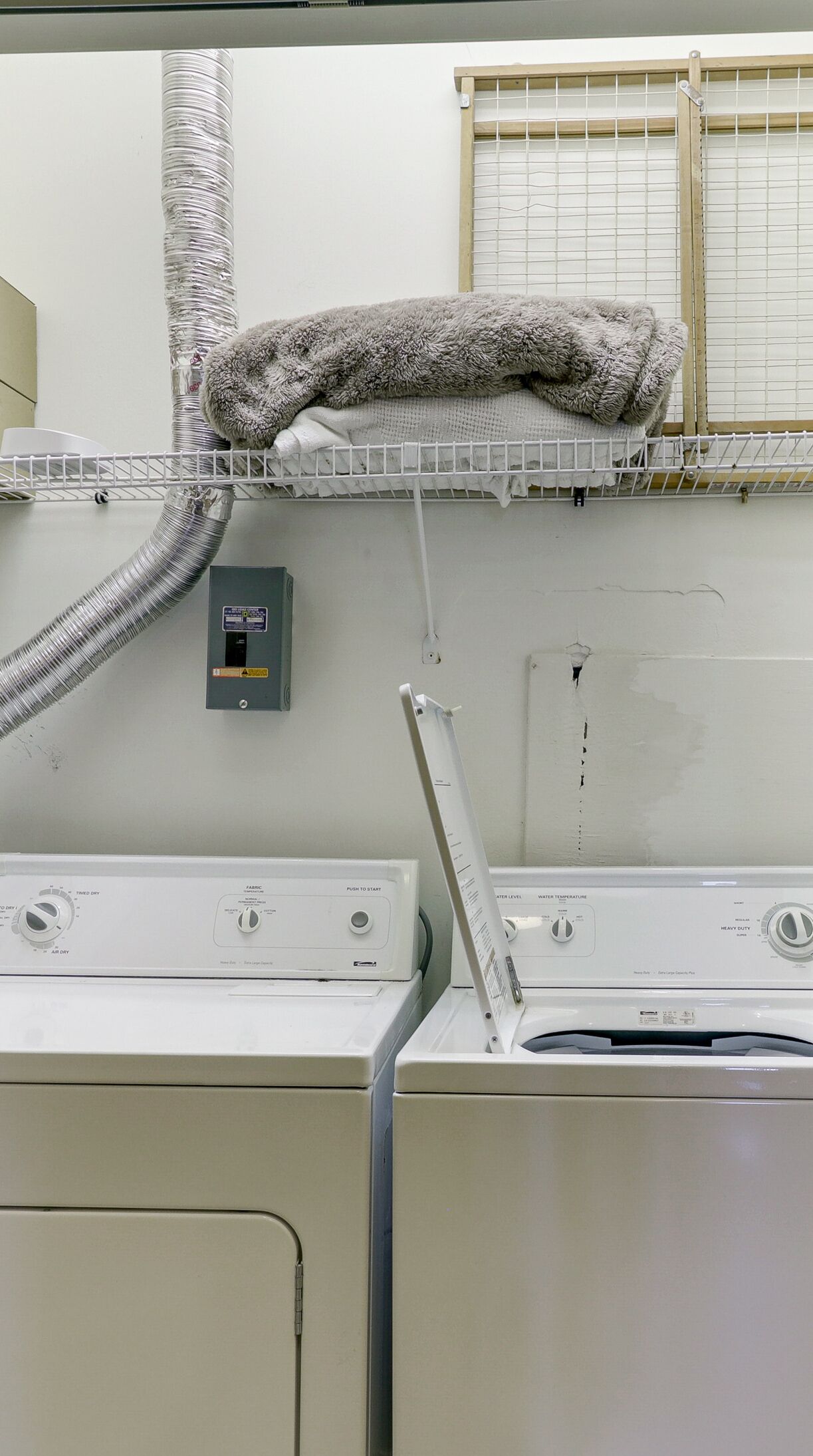 Ett tvättrum med flera torktumlare placerade ovanpå varandra och ett ventilationssystem.