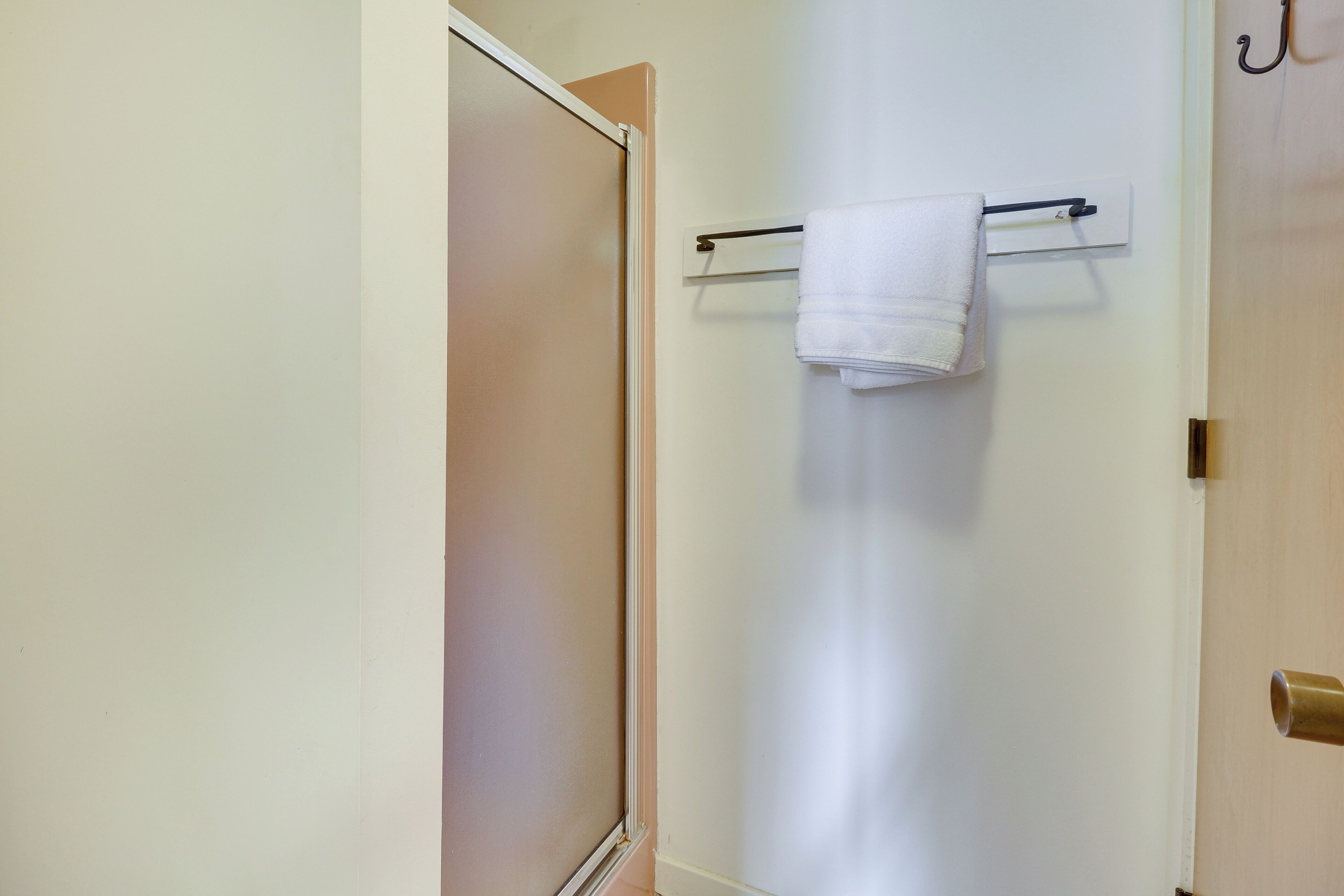 A bathroom with a towel rack, a door, and a wooden door frame.