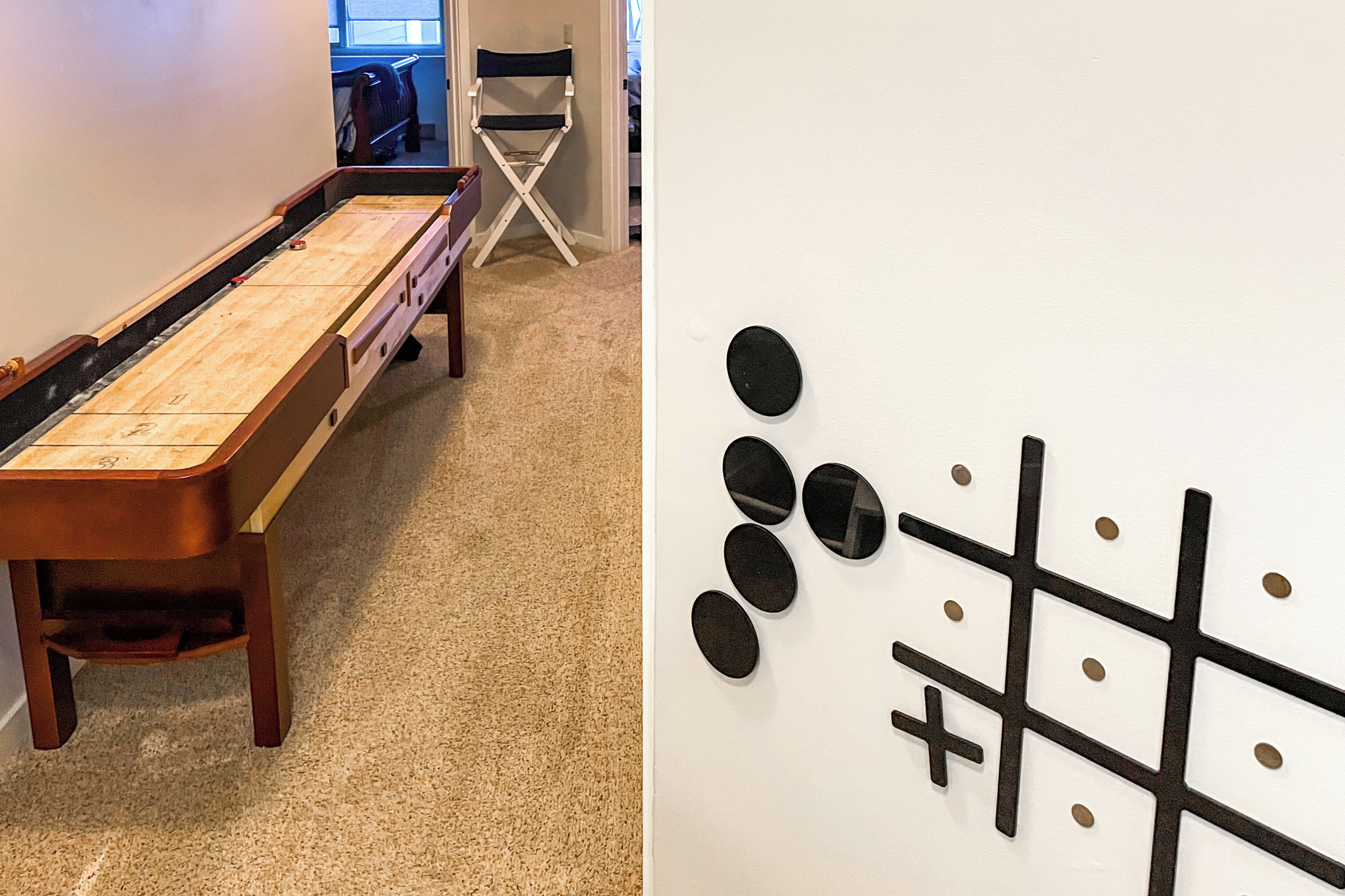 A room with a shuffleboard table and a wall with a tic-tac-toe game.