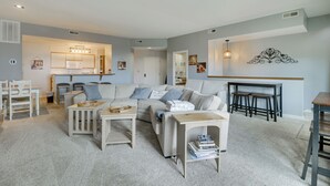 A modern living room with a sofa, coffee table, and chairs, a kitchen area with a microwave, and a dining table with stools. - All-season Fun! Wintergreen Resort Condo w/ Views (Nellysford)