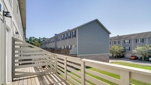 A wooden deck with a white railing, a building with a grey facade, and a clear blue sky. - Spacious D'iberville Townhome Near Beach & Casino! (D'Iberville)