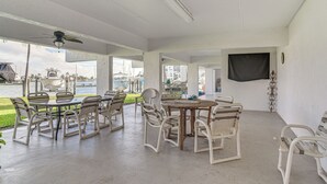 An outdoor patio area with a round table and chairs, a ceiling fan, and a view of boats and buildings in the background. - Pool, Beach Access: Waterfront Treasure Island Gem (Treasure Island)