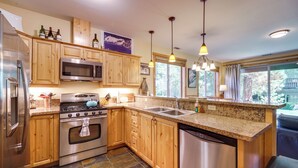 Una cocina moderna con gabinetes de madera, electrodomésticos de acero inoxidable, encimeras de granito y una isla grande con pileta.