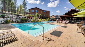Un área de piscina con sillones de descanso, un edificio de madera y un muro de piedra.