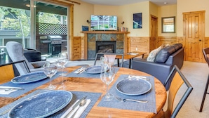 Un comedor con una mesa redonda dispuesta para cuatro personas, una chimenea y un televisor encima.