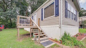 A single-story house with a wooden deck and a small staircase leading to the front door. - Creekfront Max Meadows Mobile Home With Deck! (Max Meadows)