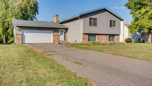 Une maison à deux étages avec un garage, des fondations en briques et une allée menant à la porte d’entrée.