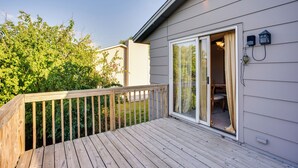 Une terrasse en bois avec une porte vitrée donnant sur une pièce qui contient une chaise et une table.