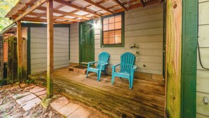 A porch with wooden beams and a green door, two blue Adirondack chairs, and a small window with blinds. - Cozy Tallahassee Home - 2 Mi to Governors Square! (Tallahassee)