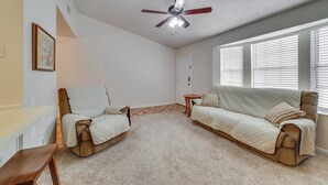 A living room with a ceiling fan, a beige sofa, a brown armchair, and a small wooden table. - Cozy Tallahassee Home - 2 Mi to Governors Square! (Tallahassee)