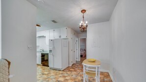 A kitchen with white cabinets, a refrigerator, and a dining area with a table and chairs. - Cozy Tallahassee Home - 2 Mi to Governors Square! (Tallahassee)