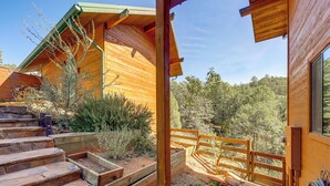 Une cabane en bois avec un escalier en pierre menant à une terrasse, le tout entouré d’un jardin clos.