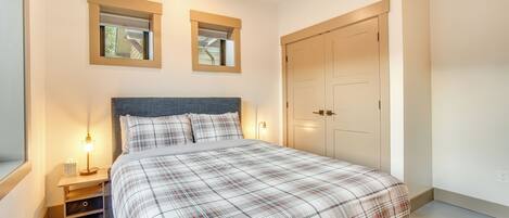 A bedroom with a bed, bedside tables, a wardrobe, and two windows.