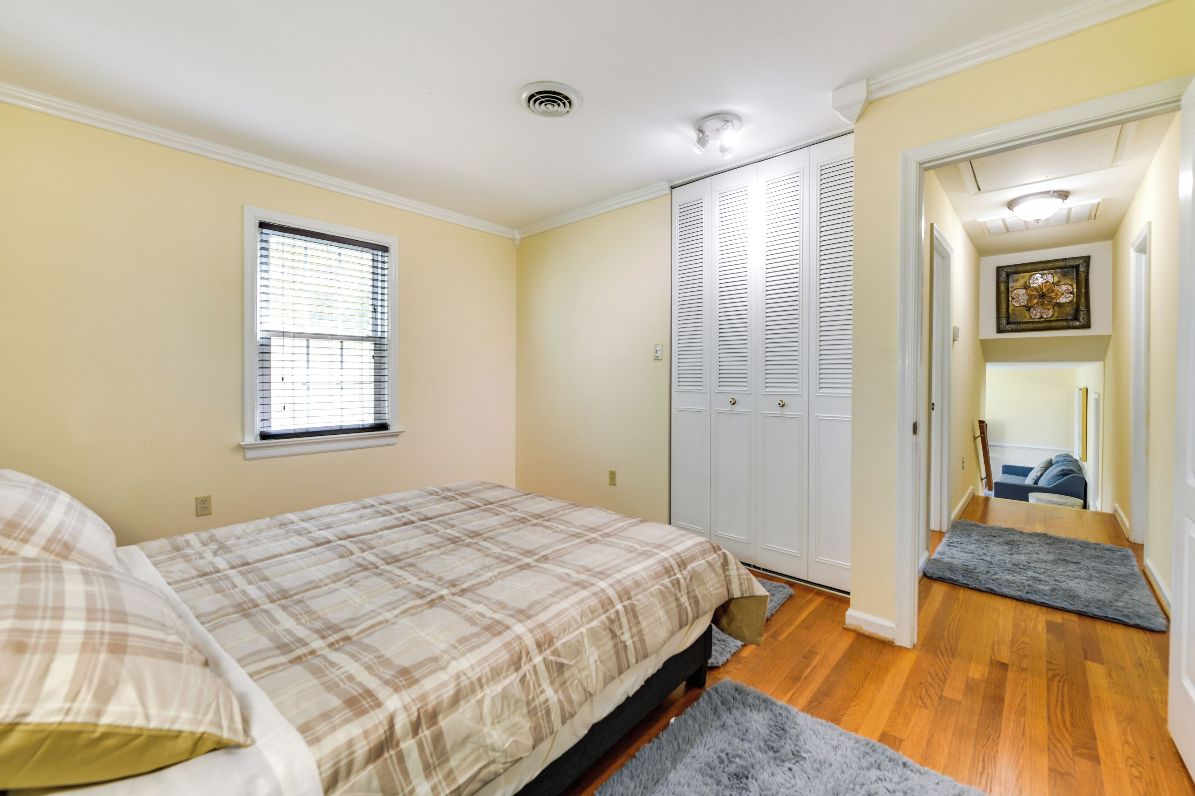A bedroom with a bed, a closet, and a hallway leading to another room.