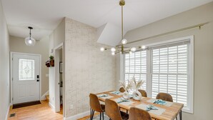 A dining area with a wooden table, brown chairs, a chandelier, and a window with blinds. - Asheville Retreat ~ 6 Mi to Biltmore & Downtown! (Asheville)
