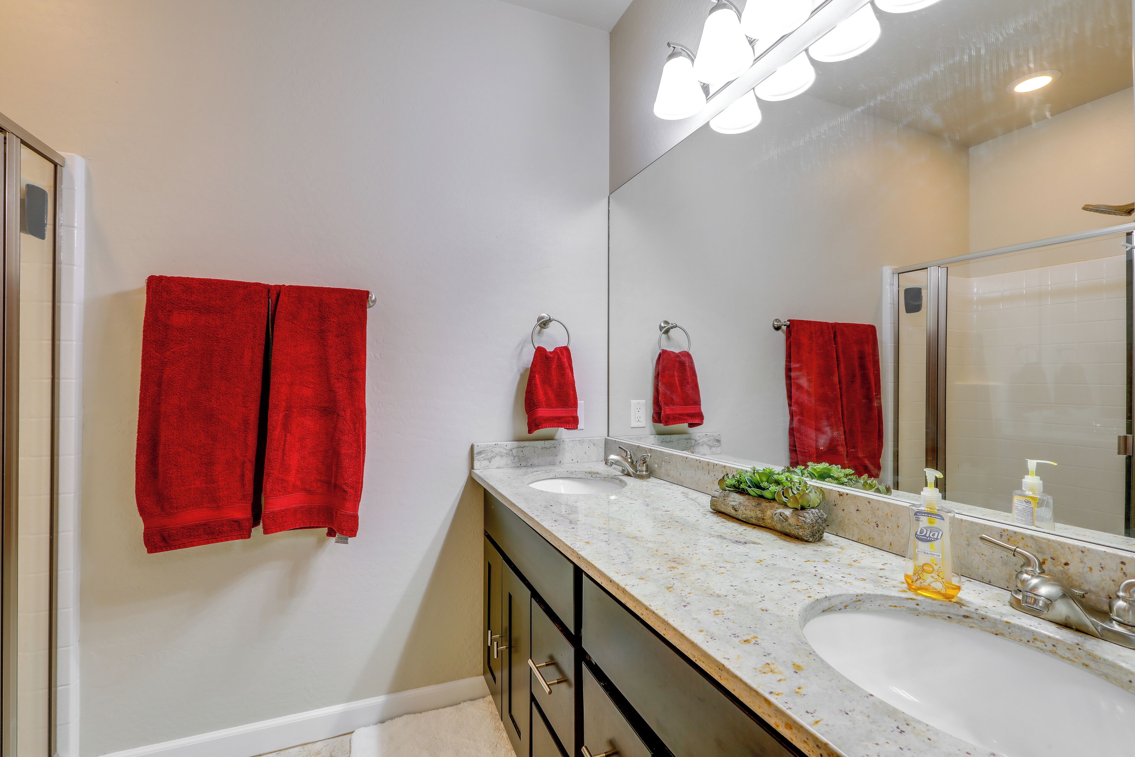 A bathroom with two sinks, a large mirror, and red towels.
