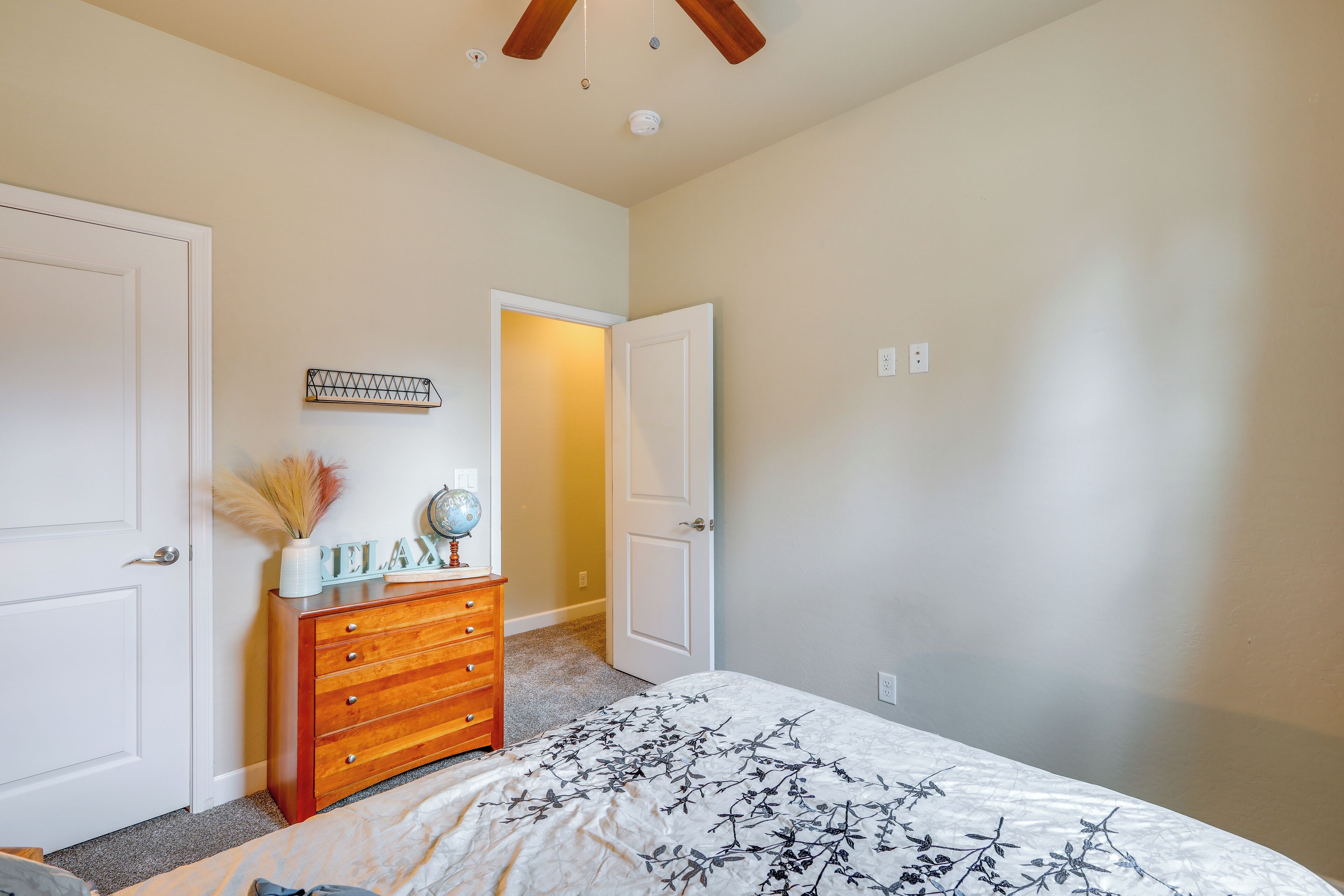 Quarto com cama, penteadeira e duas portas.