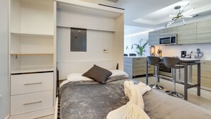 A modern bedroom with a bed, a built-in wardrobe, and a kitchenette. - High-end Miami Condo w/ City & Bay Views!!! (Miami)