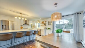 A modern kitchen with a central island, bar stools, and a dining table. - Rye Coastal Retreat w/ Deck & Outdoor Dining (Rye)