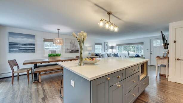 A spacious kitchen with a large island, wooden flooring, and modern lighting fixtures. - Rye Coastal Retreat w/ Deck & Outdoor Dining (Rye)