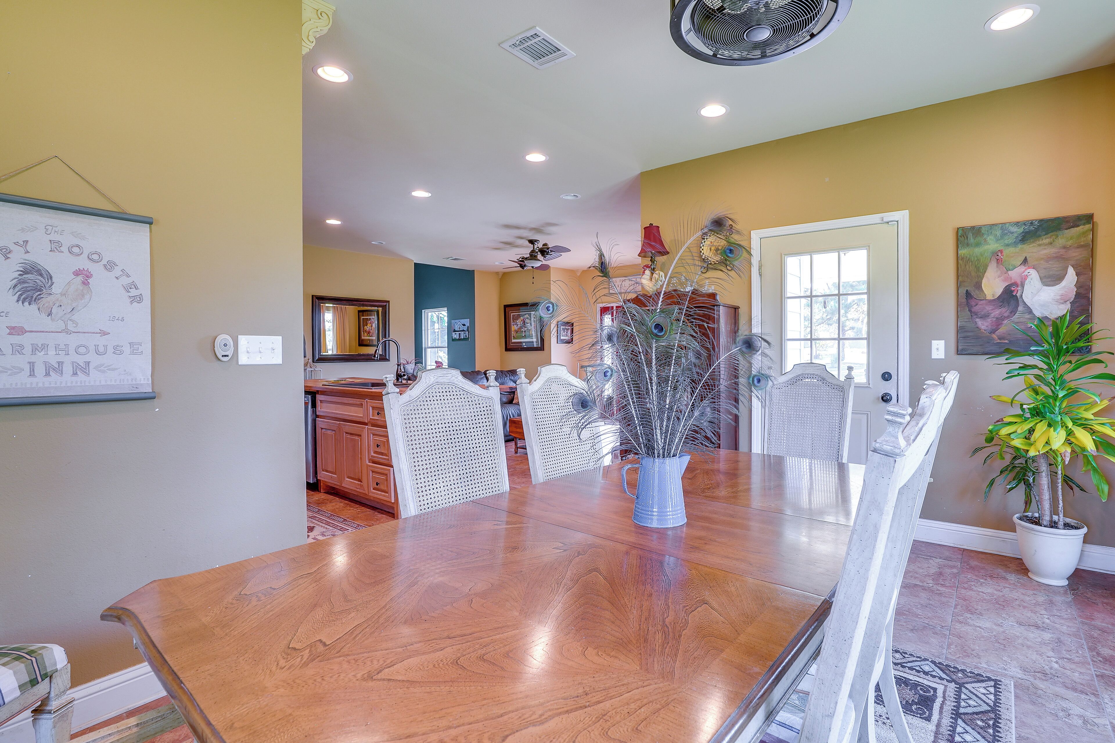 A dining area with a wooden table, chairs, and a vase with decorative branches.