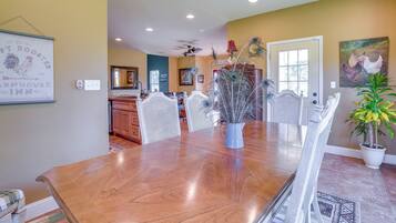 A dining area with a wooden table, chairs, and a vase with decorative branches.