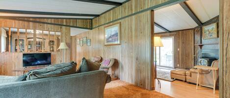 Un salon chaleureux avec un grand canapé, un téléviseur et un lambris en bois.