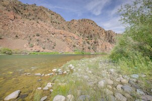 Un río de aguas claras, rodeado de terreno rocoso y vegetación escasa.