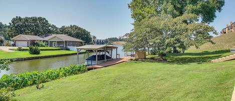 A residential area with a house, a dock, and a large tree.