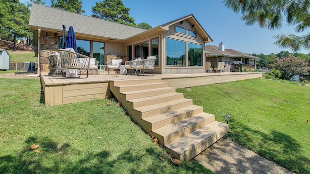 A modern house with a covered patio, a stone staircase, and a large glass window. - Peaceful Hot Springs Home: Deck w/ Water Views! (Hot Springs)