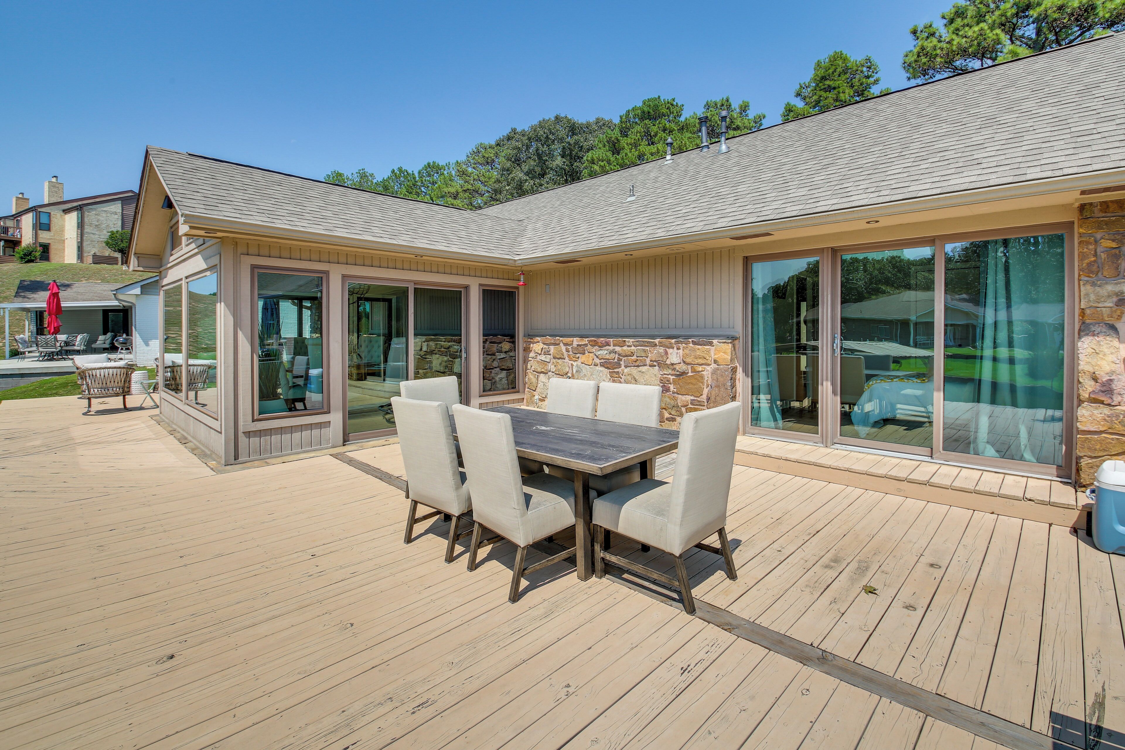 A covered patio with a wooden deck, a table with chairs, and a stone wall.