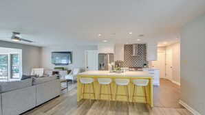 A modern kitchen with a central island, bar stools, and a dining area with a sofa and chairs. - Peaceful Hot Springs Home: Deck w/ Water Views! (Hot Springs)